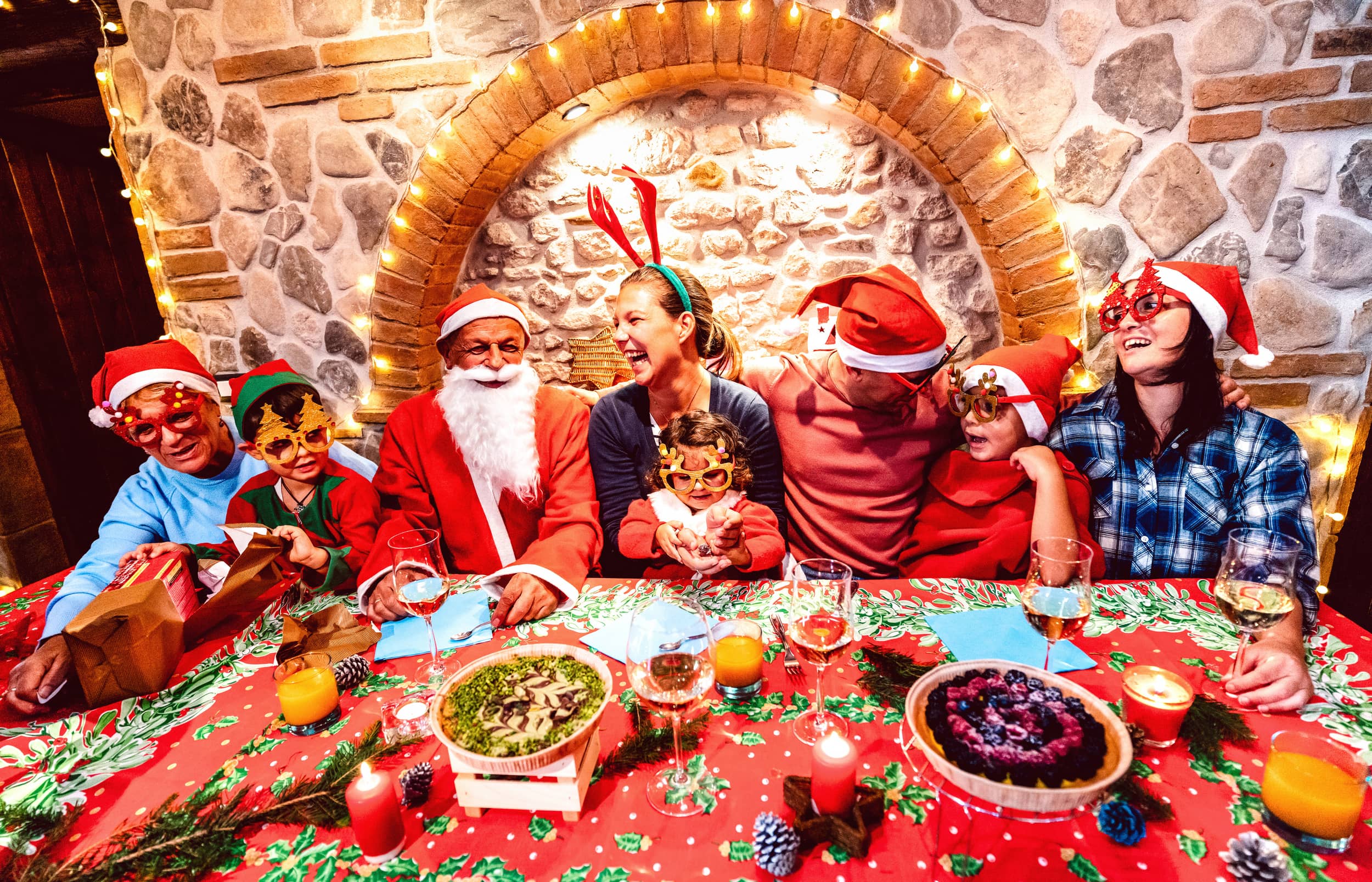 Santa sharing a festive meal with children at Bondville Model Village, surrounded by Christmas lights and decorations, creating a magical holiday experience
