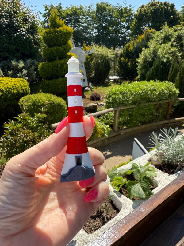 Hand holding red and white lighthouse fridge magnet at Bondville Model Village. Bondville gift shop souvenirs